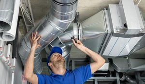 A technicians making adjustments to ductwork in a commercial building.