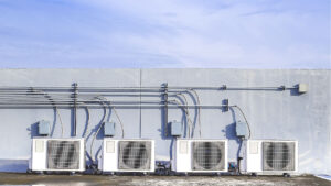 Air conditioning (HVAC) units on the roof of an industrial building with blue sky and clouds behind